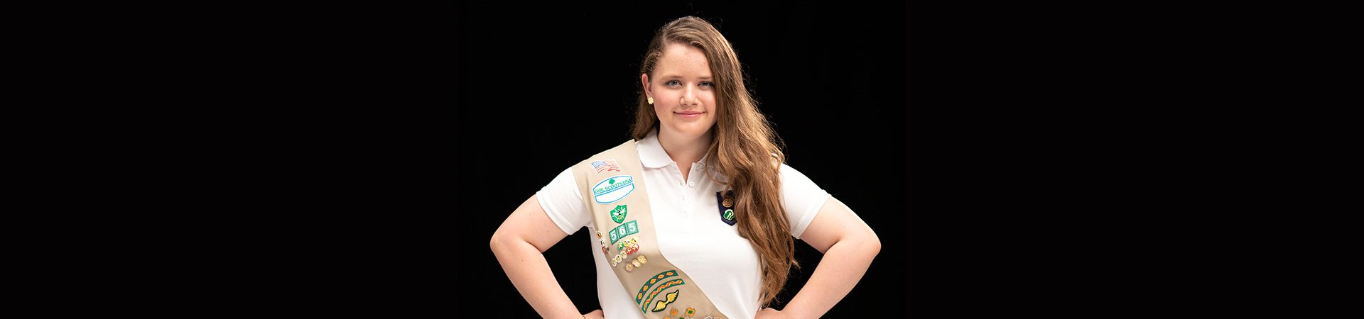  girl scout in sash standing with hands on hips 