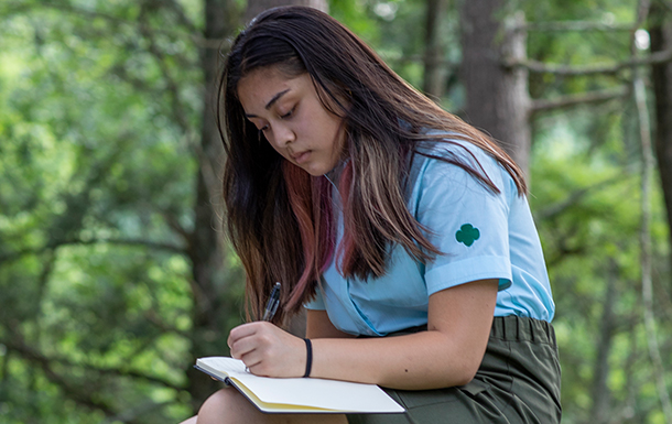 girl scout writing in a notebook