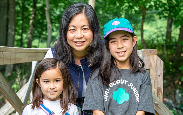 volunteer and two girl scouts outside on a bridge