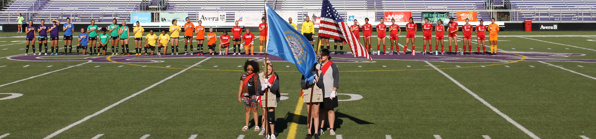  girl scouts present the colors at a soccer game 