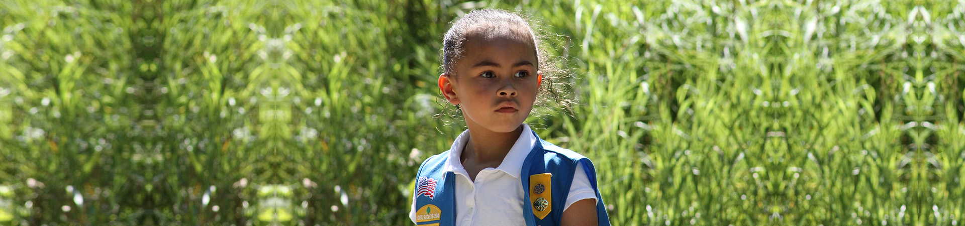  daisy girl scout outside on a trail with trees in the background 