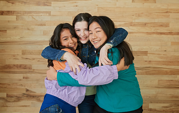 three girls standing in a circle with arms wrapped around each other