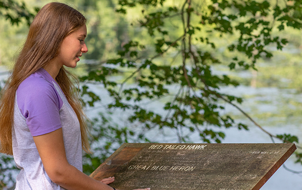 girl looking at sign on a trail