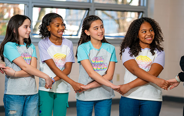 young girl scout outside cheering with hands in the air