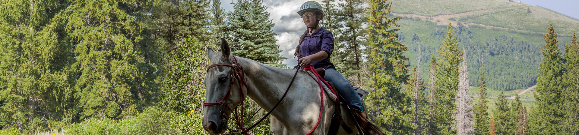  girl scout riding a horse in the mountains 