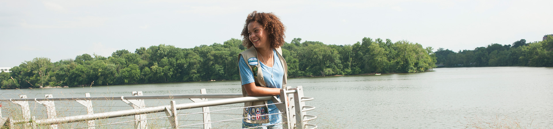  girl standing at a fence looking over a body of water 